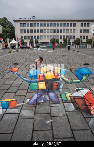 Kaiserslautern, Deutschland. 30. Juni 2023. Italienische Künstlerin Genny Gavio, die ihr 3D-Bild fertigstellt. Elf internationale Künstler aus 6 Ländern verwandelten den Stiftsplatz (Platz) in dreidimensionale Kunst, wobei das Thema „Digitalisierung und intelligente Stadt“ dieses Jahr stand. 3D Street Art nutzt die Perspektive, um eine optische Illusion des Weltraums zu erzeugen. Die Besucher konnten alle Künstler bei der Arbeit drei Tage lang beobachten. Dies ist der dritte und letzte Tag der Veranstaltung. Kredit: Gustav Zygmund/Alamy News Stockfoto
