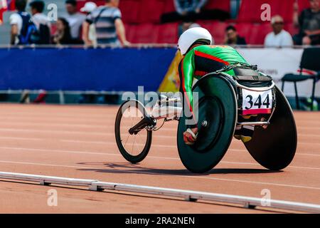 Ein Sportler im Rollstuhl-Rennstadion bei der Para-Athletik-Meisterschaft, auf seinem Kopf sitzt ein weißer Helm Stockfoto