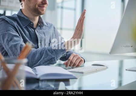 Glücklicher Geschäftsmann, der sich online mit seinem Team verbindet Stockfoto