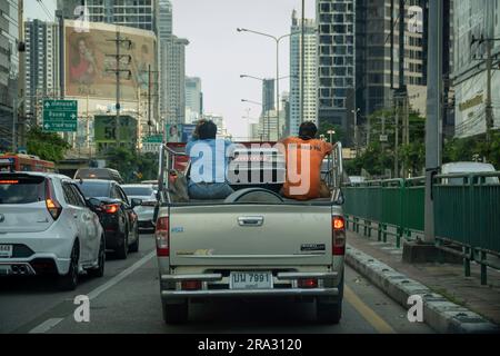 Thailändische Bauarbeiter, die zur Arbeit zurückkehren, werden am späten Nachmittag im Stau auf der Ratchadaphisek Road in Bangkok auf dem Bett eines Pick-up-Lkws gesehen. In Thailand ist es üblich, dass Arbeiter auf der Ladefläche von Pickup-Lkws transportiert werden, was häufig mit der Landwirtschaft und dem Baugewerbe in Verbindung gebracht wird, auch wenn dies aufgrund der Sicherheitsrisiken nicht empfohlen wird und nach den thailändischen Verkehrsgesetzen illegal ist. Stockfoto