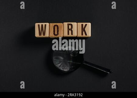 Das Wort ARBEIT ist in Holzwürfeln in schwarzen Buchstaben auf gelbem Hintergrund geschrieben. Stockfoto