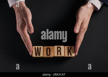 Das Wort ARBEIT ist in Holzwürfeln in schwarzen Buchstaben auf gelbem Hintergrund geschrieben. Stockfoto