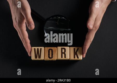 Das Wort ARBEIT ist in Holzwürfeln in schwarzen Buchstaben auf gelbem Hintergrund geschrieben. Stockfoto