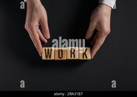Das Wort ARBEIT ist in Holzwürfeln in schwarzen Buchstaben auf gelbem Hintergrund geschrieben. Stockfoto