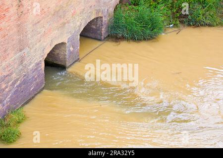 Gefährliches, unbehandeltes, giftig verschmutztes Wasser fließt aus einer städtischen Kanalisation in den Fluss. Stockfoto