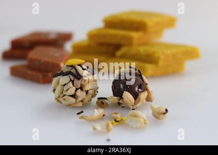 Kaju Choco Chips Laddu vor Badam Burfi und Kesar Barfi. Verschiedene indische Süßigkeiten in einem Rahmen. Allgemein verteilt zur Feier von Festivals und Stockfoto