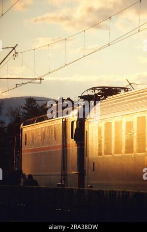 Eine vertikale Aufnahme eines Zuges, der auf einer malerischen Eisenbahnstrecke bei einem wunderschönen Sonnenuntergang fährt Stockfoto