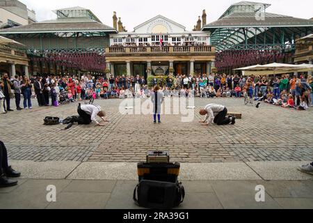 Überfüllter Londoner Platz, Covent Garden Market, mit Künstlern, Straßenkünstlern, die Fans unterhalten. Der Markt ist voller Restaurants, Bars und Shops. Stockfoto