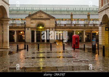 Covent Garden Market an einem Regentag in London. Rote Telefonzellen, geschlossene Geschäfte und leere Straßen. Ein Londoner Wahrzeichen und beliebter West End Square. Stockfoto