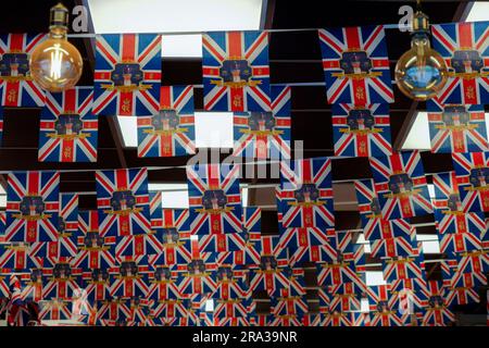 King-Charles-Krönungswoche in England hängen Jack-King-Charles-III-Krönungsflaggen in einem Souvenirladen im Piccadilly Circus, London. Stockfoto