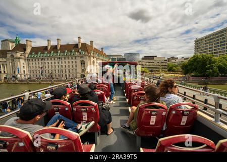 Roter Doppeldeckerbus mit offenem Oberdeck, Hop-on-Hop-off-Busfahrt über die Themse, Touristen besichtigen Londons wichtigste Sehenswürdigkeiten, historische Stätten und erhalten einen Blick auf die Skyline der Stadt. Stockfoto