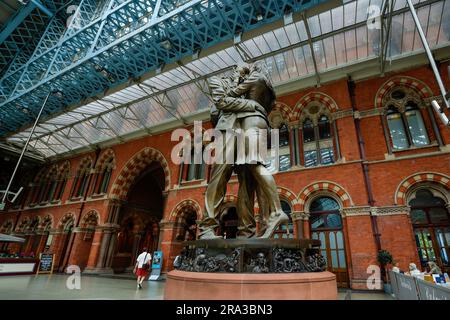 Der Bahnhof St. Pancras in London, England, zeigt eine berühmte Statue mit dem Namen „The Meeting Place“ ein Paar, das umarmt, um die Romantik des Reisens zu zeigen. Stockfoto