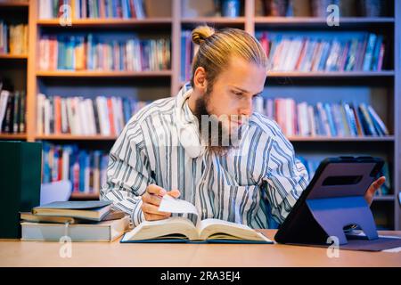 Porträt des Menschen beim Lesen von Büchern und Arbeiten in der Lehrbibliothek Stockfoto