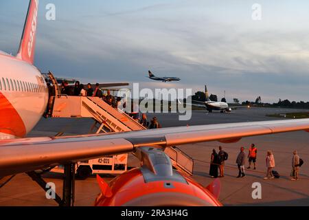 Am Abend, easyJet Flugzeug mit Passagieren, die hinten einsteigen, mit einem anderen Flugzeug, das an Land kommt und das dritte auf der Landebahn, Flughafen Porto, Portugal Stockfoto