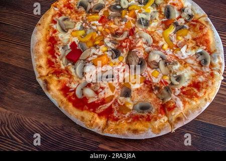 Pilzpizza: Eine leckere Pizza mit Tomatensoße, geschmolzenem Käse, aromatischen Pilzen, lebendigem Paprika und Zuckermais, Alle auf einem evu Stockfoto