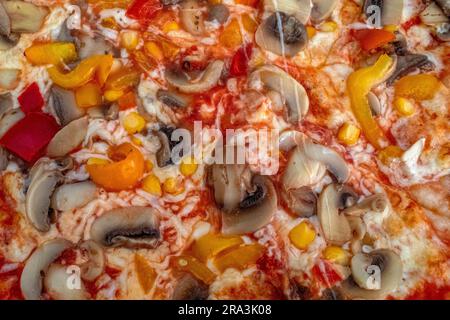 Pilzpizza: Eine leckere Pizza mit Tomatensoße, geschmolzenem Käse, aromatischen Pilzen, lebendigem Paprika und Zuckermais, Alle auf einem evu Stockfoto