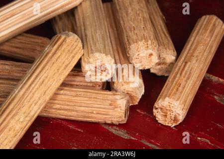 Ein Stapel von Passstiften auf rotem Hintergrund, Passstifte zum Verbinden von zwei Holzstücken, Gelenken, Schreinern Stockfoto