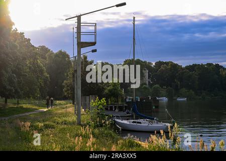 Potsdam, Deutschland. 30. Juni 2023. Die untergehende Sonne erhellt die Vegetation am Jungfernsee in der Nähe des Schlosses Cecilienhof am Abend trotz dunkler Regenwolken. Derzeit ist das Wetter durch Regen und sonnige Strecken verunsichert. Kredit: Jens Kalaene/dpa/ZB/dpa/Alamy Live News Stockfoto