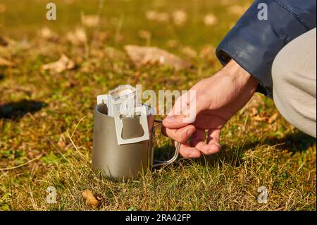 Der Tourist macht Tropfkaffee vor dem Hintergrund der wunderschönen Herbstberge und Natur Stockfoto