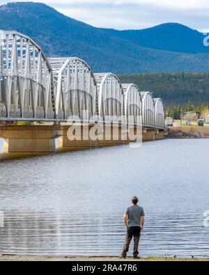 Große, von Menschenhand geschaffene Stahlbrücke, die sich über die Nisutlin Bay in der Ortschaft Teslin erstreckt und im Frühling zum Yukon River im Norden Kanadas floss Stockfoto