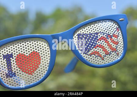 Patriotische Sonnenbrille. Ich liebe die Vereinigten Staaten, die USA, die USA, Amerika. Vor einem bewaldeten Hintergrund und blauem Himmel. Konzentrieren Sie sich auf den Vordergrund. Stockfoto