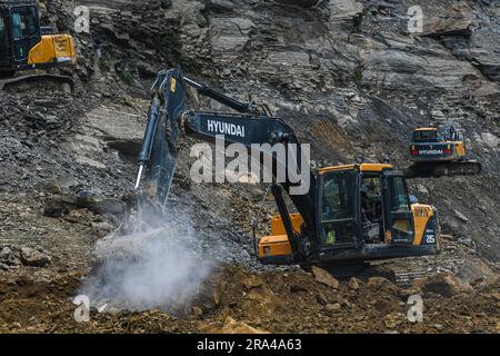 26. Juni 2023, Churachandpur, Manipur, Indien: Hyundai-Bagger brechen Felsen und entfernen Trümmer nach einem Erdrutsch entlang des National Highway 150 nach starkem Monsunregen am Stadtrand von Churachandpur. Manipur Churachandpur befindet sich in einer hügeligen Region und ist anfällig für Erdrutsche, insbesondere während der Monsunzeit. Die starken Regenfälle und steilen Hänge in diesem Gebiet erhöhen das Risiko von Erdrutschen. Faktoren wie Bodenerosion, Entwaldung, unsachgemäße Landnutzung und Bautätigkeiten können ebenfalls zum Auftreten von Erdrutschen beitragen. (Kreditbild: © Biplov Bhuyan/SOPA Bilder via ZUMA Pres Stockfoto