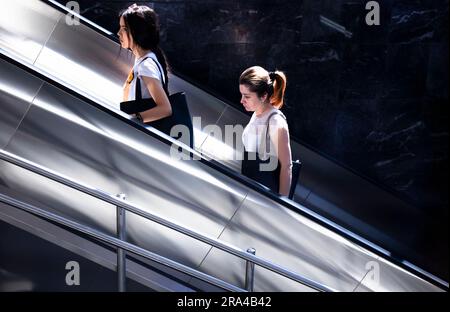 Belgrad, Serbien - 15. Juni 2022: Zwei Frauen, die an einem sonnigen Tag mit der U-Bahn-Rolltreppe nach oben fahren Stockfoto