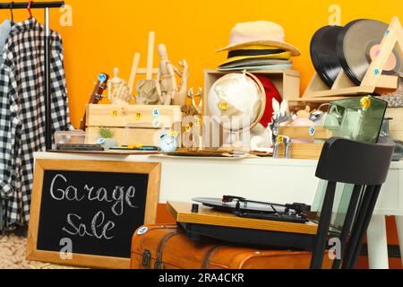 Schild Garage Sale steht an der Tafel in der Nähe von vielen verschiedenen Sachen Stockfoto