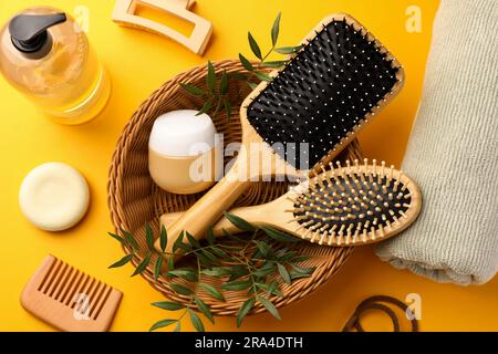 Holzbürsten und verschiedene Haarprodukte auf orangefarbenem Hintergrund, über der Ansicht Stockfoto