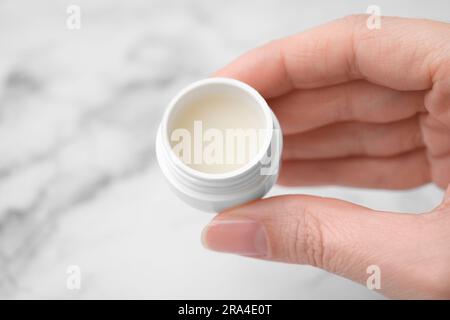 Eine Frau, die ein Glas Vaseline auf einem hellen Hintergrund hält, Nahaufnahme Stockfoto