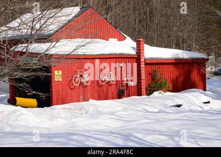 Ein roter Antiquitätenladen hebt sich in einer Winterszene im ländlichen New Hampshire hervor Stockfoto