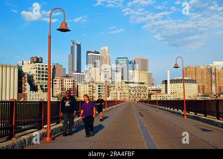 Die Leute machen einen frühen Morgenspaziergang auf der Stone Arch Bridge, einer Fußgängerüberquerung in Minneapolis, Minnesota Stockfoto
