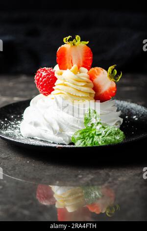 Knusprig gebackenes italienisches Baiser mit Marshmallow, gefüllt mit Chantilly Creme, garniert mit frischen Erdbeeren und Himbeeren. Stockfoto