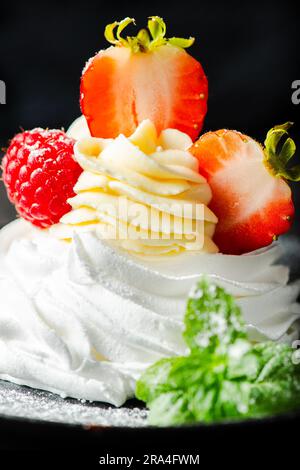 Knusprig gebackenes italienisches Baiser mit Marshmallow, gefüllt mit Chantilly Creme, garniert mit frischen Erdbeeren und Himbeeren. Stockfoto