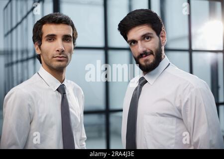 Zwei seriöse junge Geschäftsleute, die im Amt stehen Stockfoto