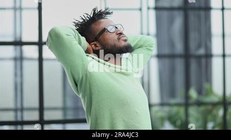 Der junge Mann hat sich die Hände hinter den Kopf geklammert. Stockfoto