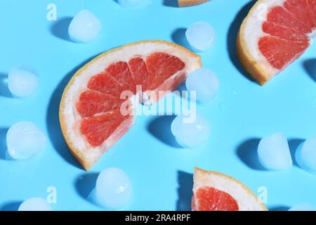 Grapefruitscheiben mit Eiswürfeln auf blauem Hintergrund Stockfoto