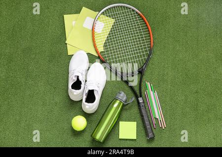 Sneaker mit einer Flasche Wasser, Tennisball, Schläger und verschiedene Schreibwaren auf farbigem Hintergrund Stockfoto