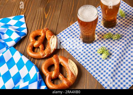 Bayerische Flagge, Tassen mit Bier und Brezeln auf Holzhintergrund Stockfoto