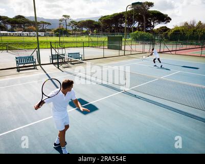 Verschiedene männliche Tennisspieler spielen auf einem sonnigen Freiluftplatz, Kopierbereich Stockfoto