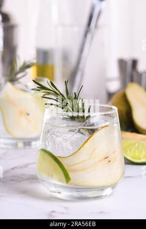 Gin Cocktail mit Limette, Rosmarin, reifer Birne und Tonic. Dieses erfrischende Bio-Getränk ist voller lebhafter Aromen und aromatischer Kräuter. Stockfoto