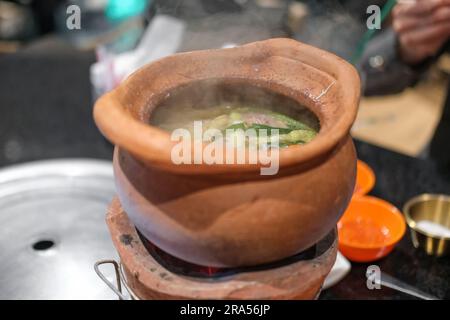 Jim Joom, thailändischer Hot Pot aus dem Nordosten Thailands, enthält Schweinefleisch, Gemüse und Glasnudeln in einer Tonschüssel Stockfoto