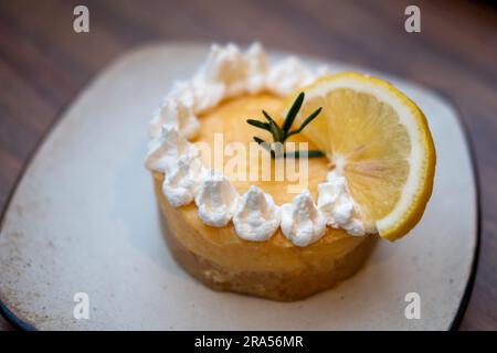 Zitronentorte mit Sahne und Zitrone, serviert auf dem Teller Stockfoto
