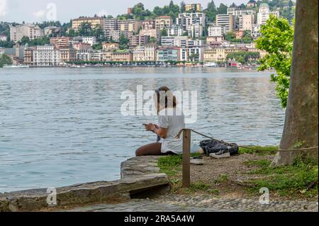 Eine Frau entspannt sich im Ciani Park in Lugano, Schweiz, und hört Musik über Kopfhörer Stockfoto