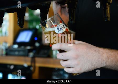 Ein Dateifoto vom 28. Oktober 08/18, auf dem ein Barkeeper ein Kronenbourg-Bier in einem Pub in Fulham, London, einschenkt. Eine neue Kampagne wurde gestartet, um die „düstere Wahl“ zu beenden, mit der sich das Personal in der Bar und im Restaurant am Ende der Nachtschichten wieder nach Hause begeben musste. Der Scottish Trades Union Congress (STUC) fordert, dass diese Arbeitnehmer von ihren Arbeitgebern nach Hause transportiert werden. Sie hat ihre Kampagne "sicheres Zuhause" wieder in Gang gebracht, wobei die Forderungen mit der STUC-Jugendkonferenz in Glasgow dieses Wochenende zusammenfielen. Ausgabedatum: Samstag, 1. Juli 2023. Stockfoto