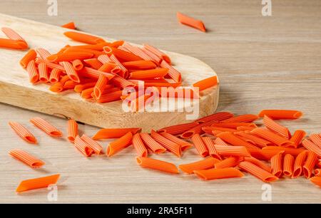 Italienische Pasta in hellem Rot ist auf dem Küchentisch verstreut. Nahaufnahme. Stockfoto