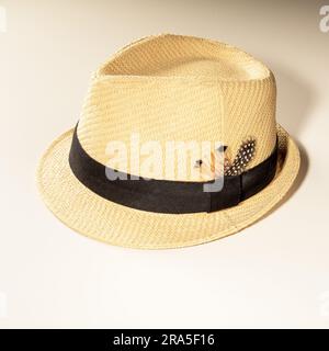 Sonnenhut mit Band und Vogelfeder aus leichtem Stroh für Urlaub auf hellem Hintergrund. Stockfoto