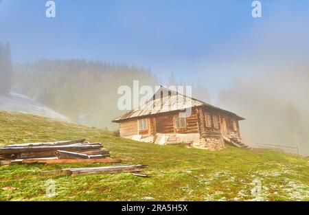 Herbst Landschaft mit den ersten unerwarteten Schnee und Herbst Laub. Alte Holzhütten auf einem berghügel Stockfoto