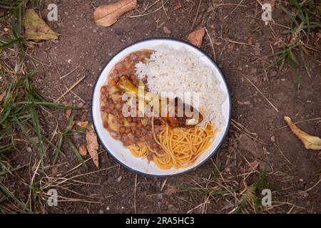 Merienda de la Chakra mit Huhn, Reis und Hülsenfrüchten. Traditionelles Gericht der Menschen, die auf den Feldern des peruanischen Dschungels arbeiten. Stockfoto