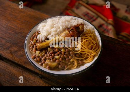 Merienda de la Chakra mit Huhn, Reis und Hülsenfrüchten. Traditionelles Gericht der Menschen, die auf den Feldern des peruanischen Dschungels arbeiten. Stockfoto